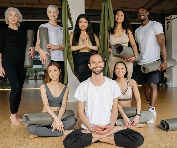A diverse group of people smiling during a yoga class.